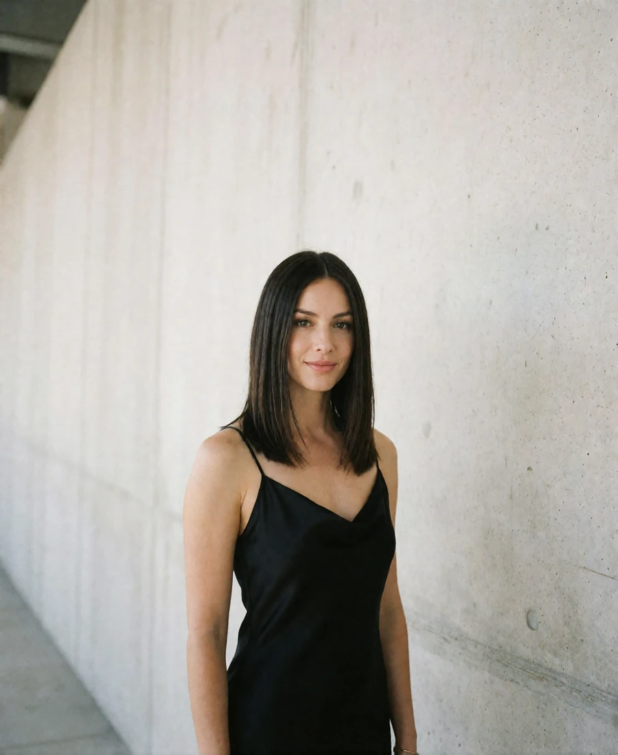 Elegant woman with sleek shoulder-length hair in a black slip dress beside a concrete wall in the Dallas Arts District, an example Dallas member profile photo